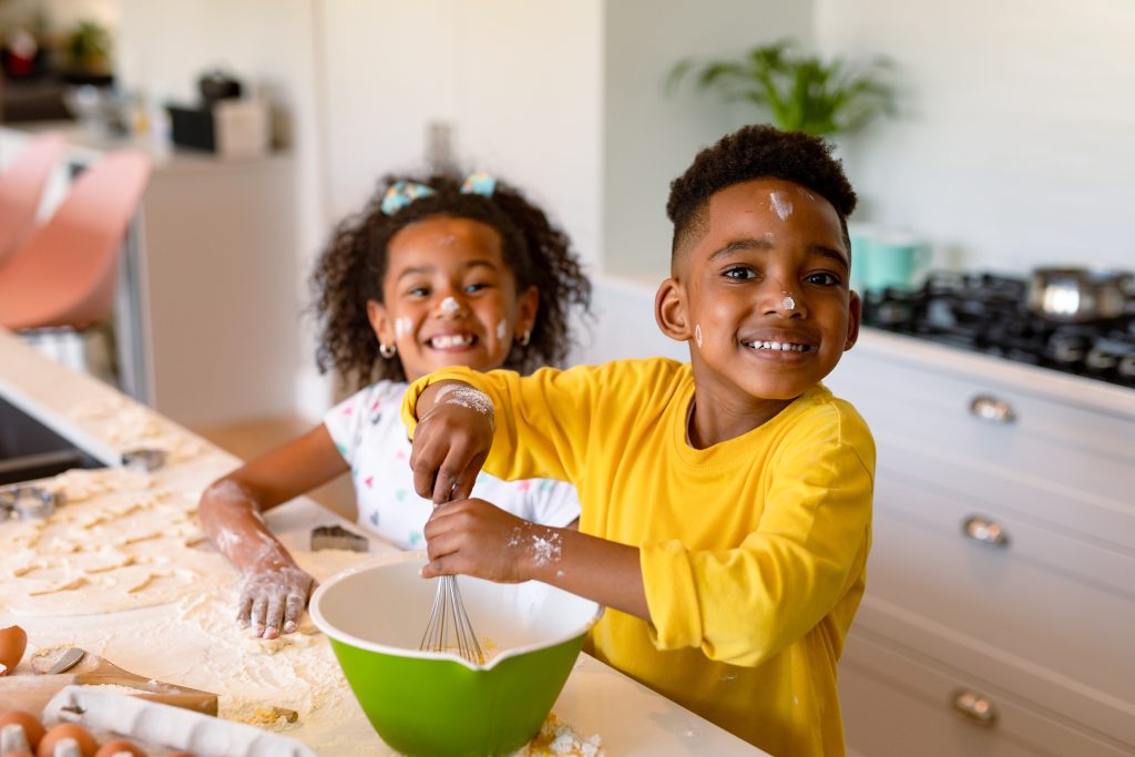 Deux enfants noirs faisant la cuisine joyeusement en en mettant partout